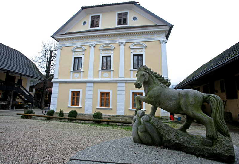 Zunanjost turistične kmetije. V ospredju je kip konja.