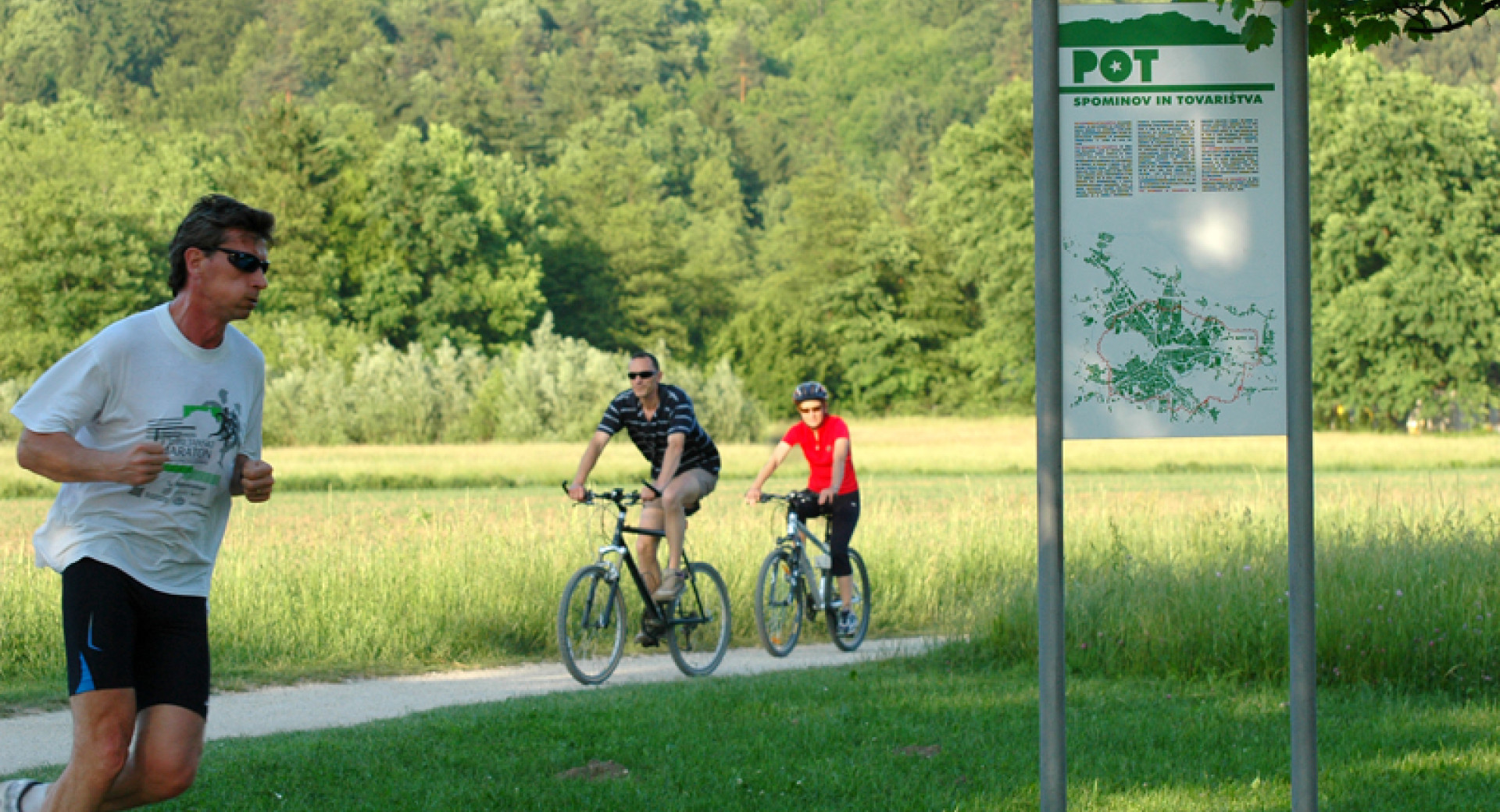 Tekač in v ozadju kolesarja na Poti spominov in tovarištva v Ljubljani.