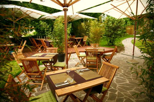 A garden with tables, chairs, and patio umbrellas.