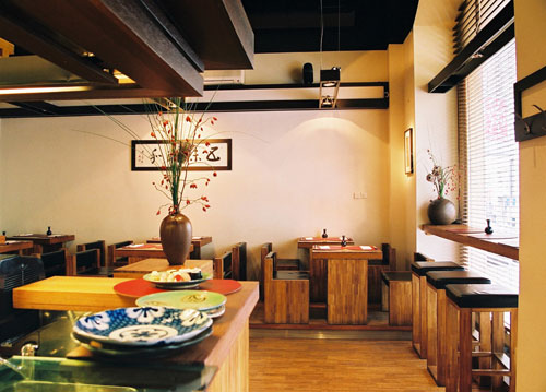 Notranjost restavracije z lesenimi mizami in stoli.