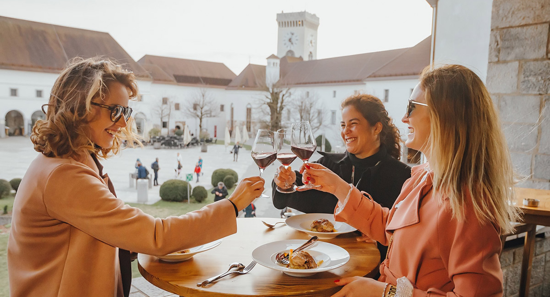 Tri prijateljice na Ljubljanskem gradu azdravljajo s kozarcem vina.