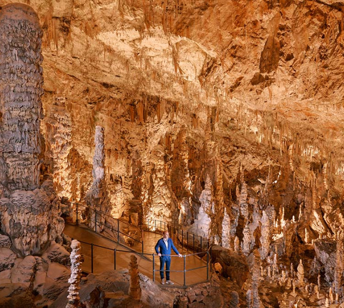 Ein Besucher in der Höhle mit vielen Stalagmiten und Stalaktiten.