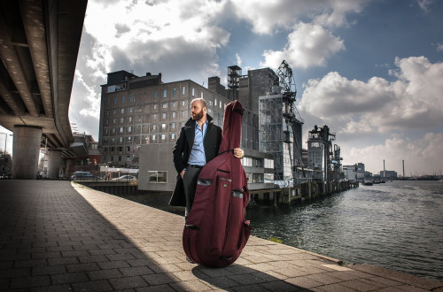glasbenik z instrumentom v torbi, v ozadju obala 
