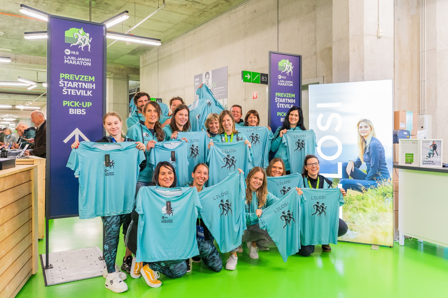 The runners pose for a photo, each holding a light blue T-shirt in their hands.
