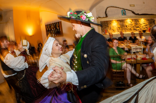Par v narodnih nosah plese v objemu in se smeji.