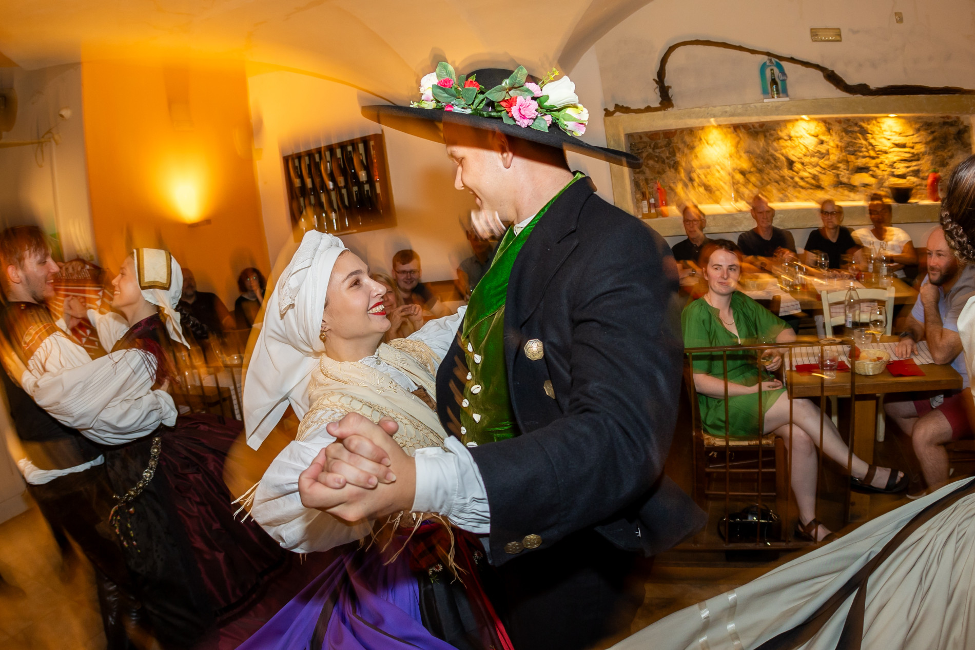 Par v narodnih nosah plese v objemu in se smeji.