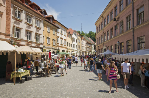 Ljudje se sprehajajo na ulici med stojnicami v starem delu mesta.