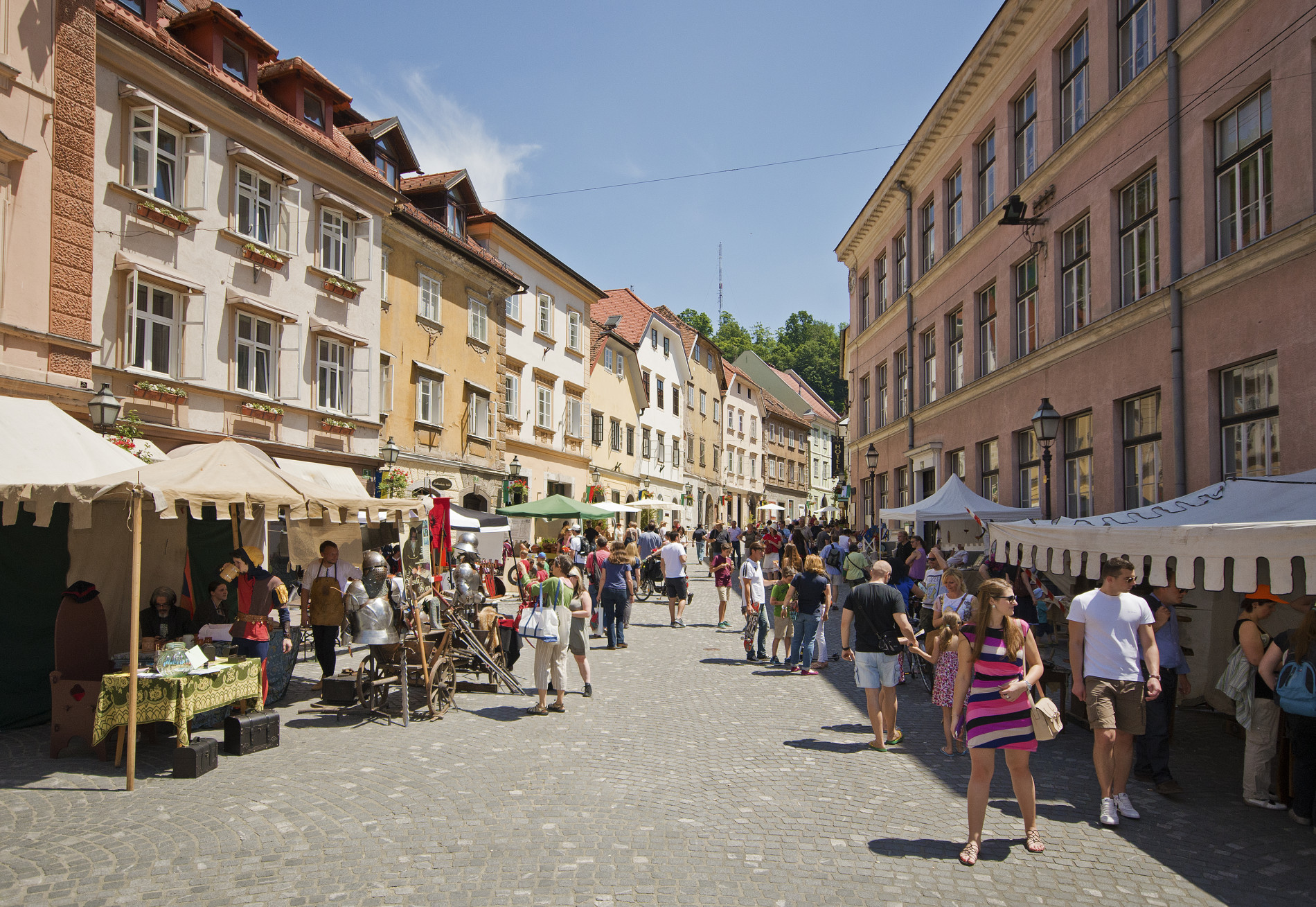 Ljudje se sprehajajo na ulici med stojnicami v starem delu mesta.