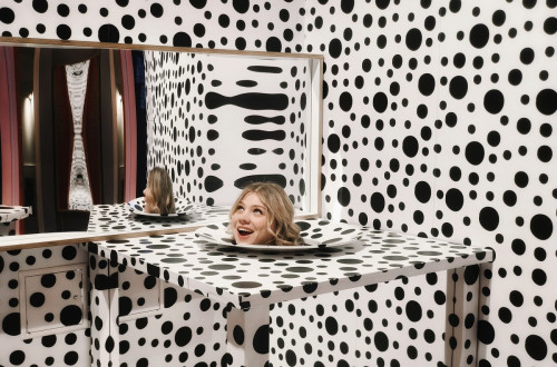 Illusion of a head on a plate in the middle of a black-and-white polka-dotted room.