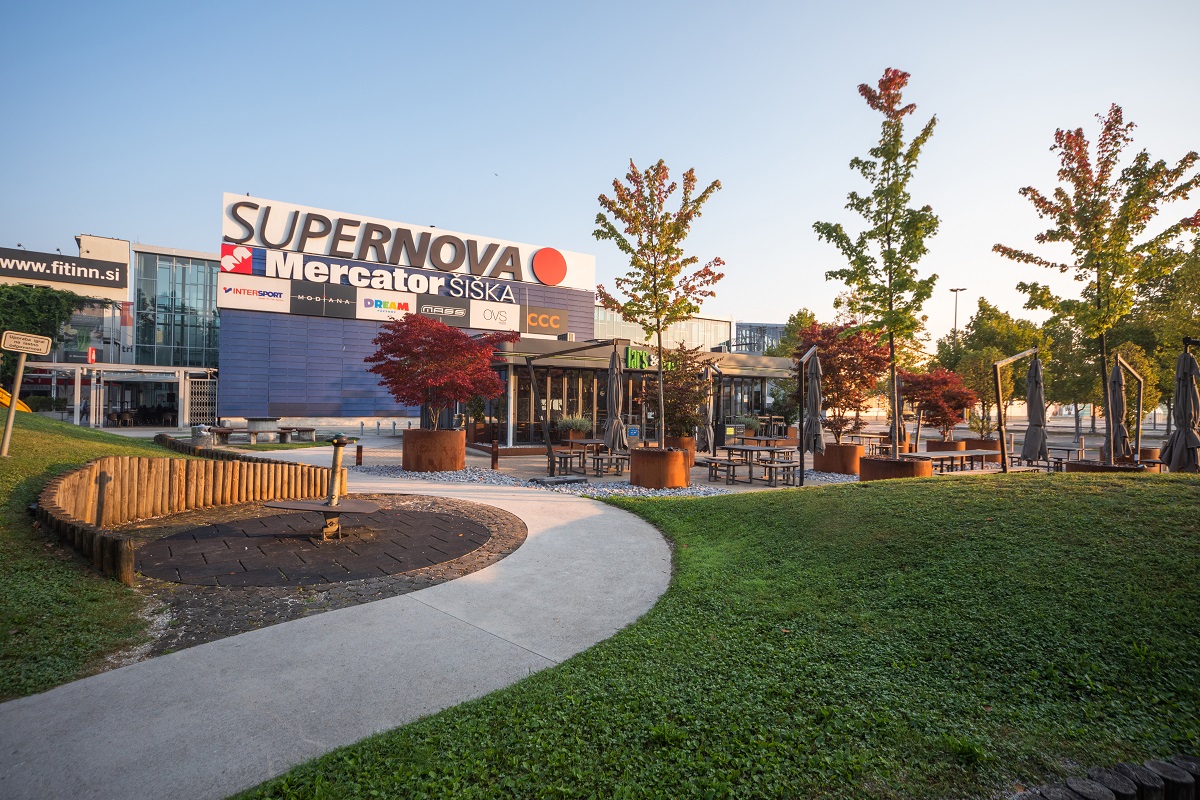 A close-up view of the exterior of the shopping centre with greenery and the path leading to it.