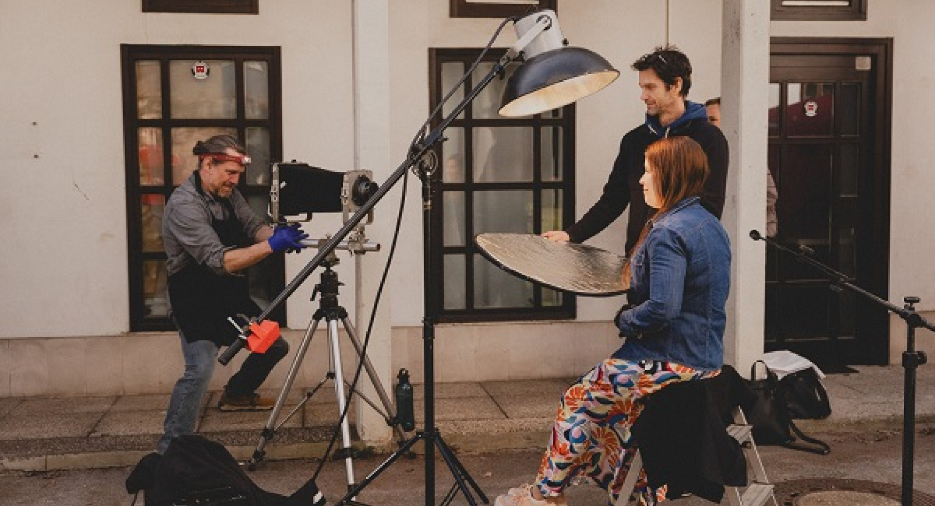 A woman under the light, a male cameraman, and another man during a stage setup.