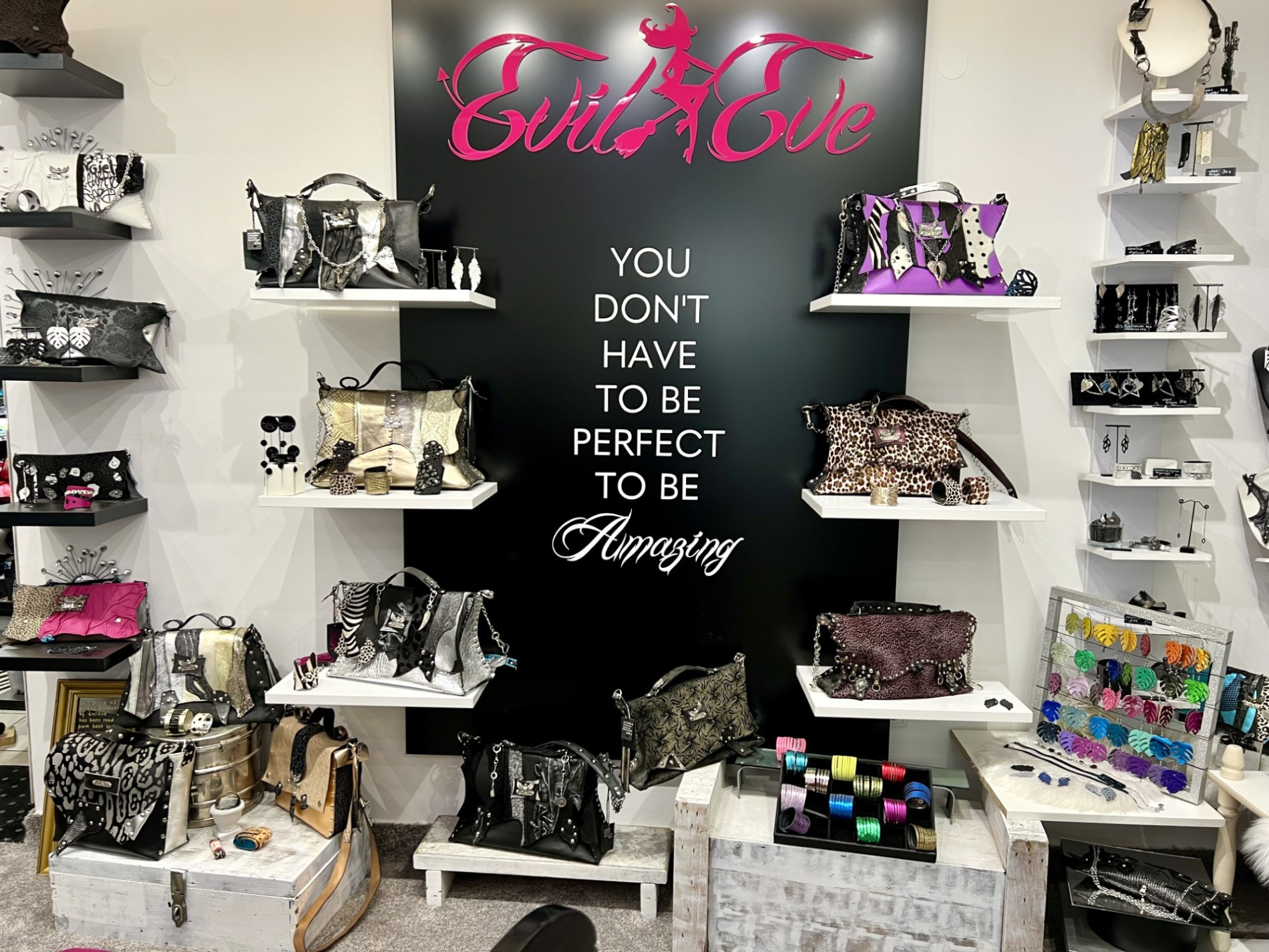 Various handbags and accessories are placed along the wall with a black background. 