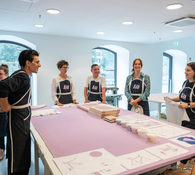 Presentazione dei materiali al Center Rog. I visitatori sono radunati intorno a un tavolo.