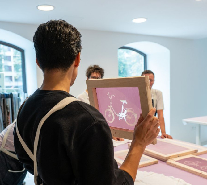 Un uomo mostra un modello per T-shirt. I visitatori ascoltano.