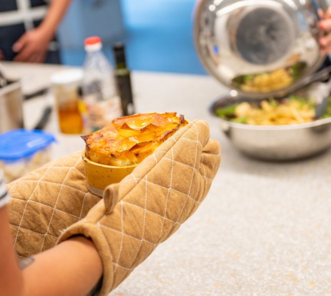 Zenska z zascitnimi rokavicami v rokah drzi peceno slano pito.