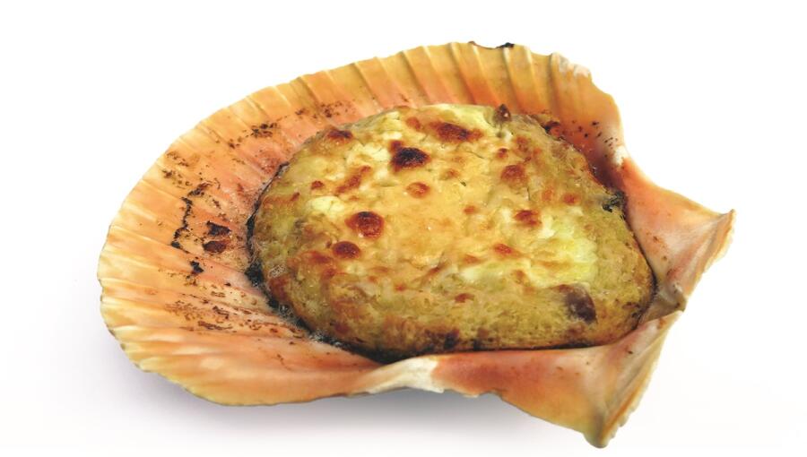 In the shell, there is a baked seafood dish that is golden brown and slightly crisped on top.