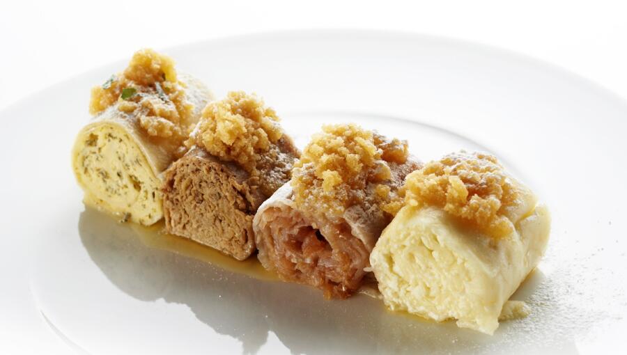 On the plate, there are four different wraps, each garnished with breadcrumbs.
