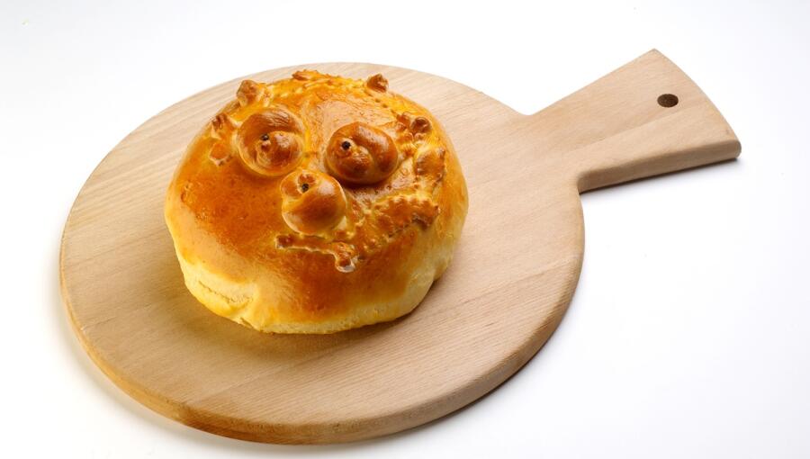 Round, golden-brown bread, placed on a wooden board.