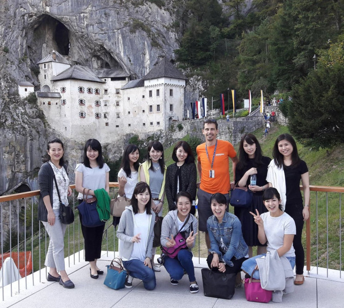 Skupina ljudi pred gradom, ki je vzidan v steno.