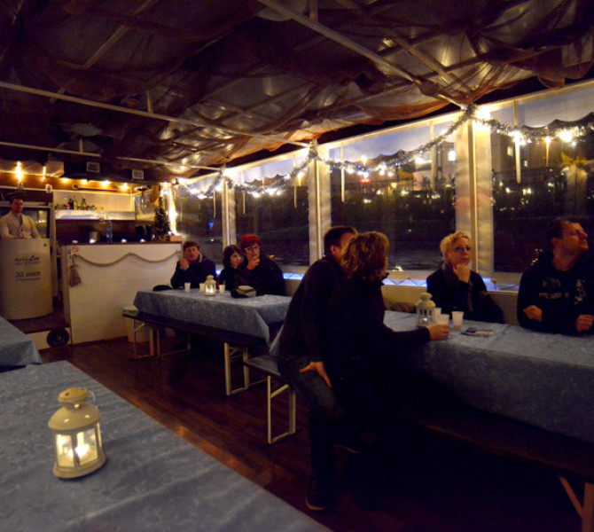 Innenraum des geschmückten Bootes. Menschen genießen die Fahrt und den Blick auf die geschmückte Stadt.
