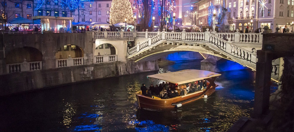Ladjica na reki Ljubljanica v praznicno okrasenem centru mesta.
