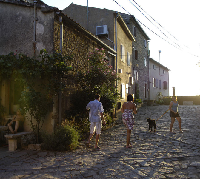 Druzina s psom na ulicah starega mesta ob soncnem zahodu.