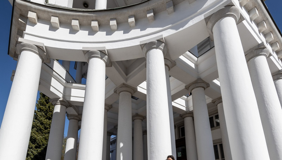 Large white columns shaping a building. A woman in green in front.