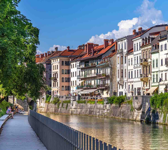 Der Fluss durch die Stadt, auf der rechten Seite Häuser, auf der linken ein Park mit einem Spazierweg.