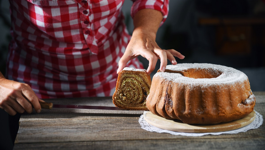 A woman taking out a slice of walnut potica.