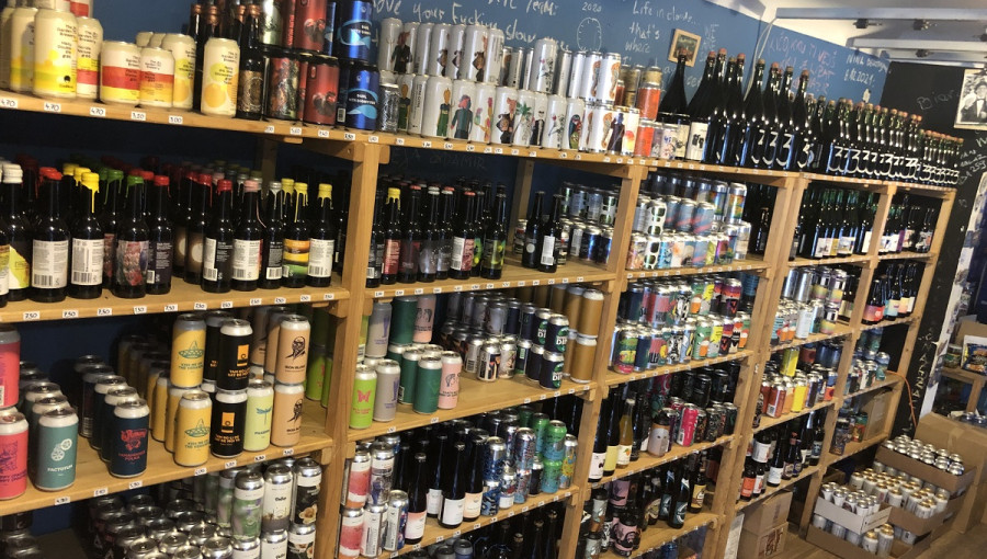 Hundreds cans and bottles of beer on shelves.
