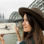 A profile photograph of a young woman holding a sketch. A large steel bridge in the background.