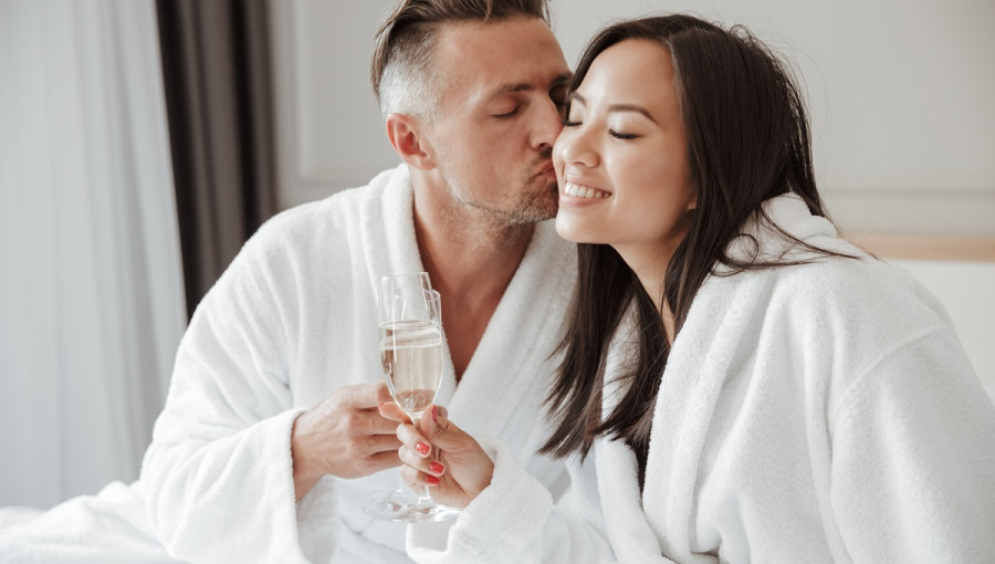A man and a woman in bathrobes drinking champagne.