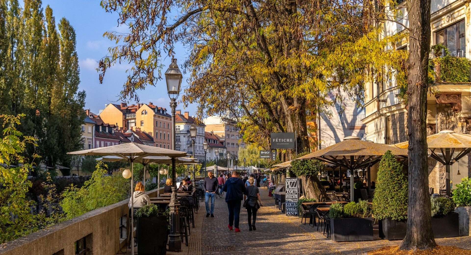 Ljudje se sprehajajo po mestu ob vodi.