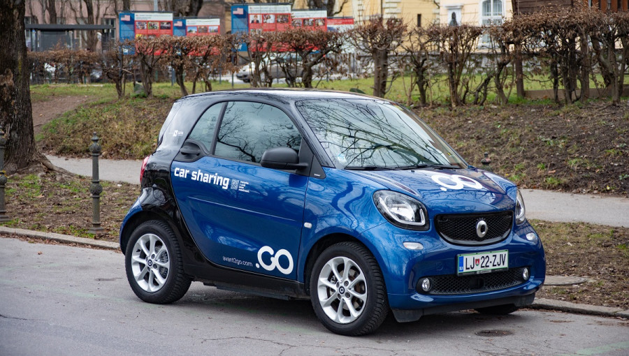 A blue co-sharing car driving on the road.