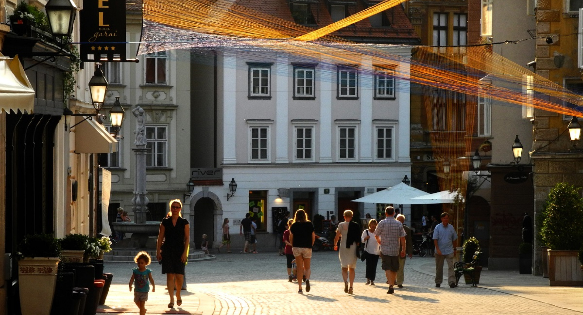 People walking in a big sun-lit city square.