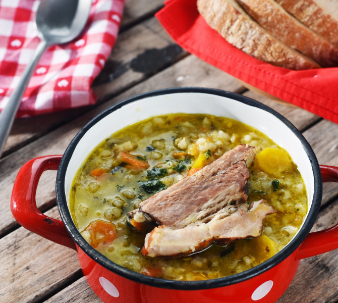 Pot with stew in the foreground. Slices of bread in the background.