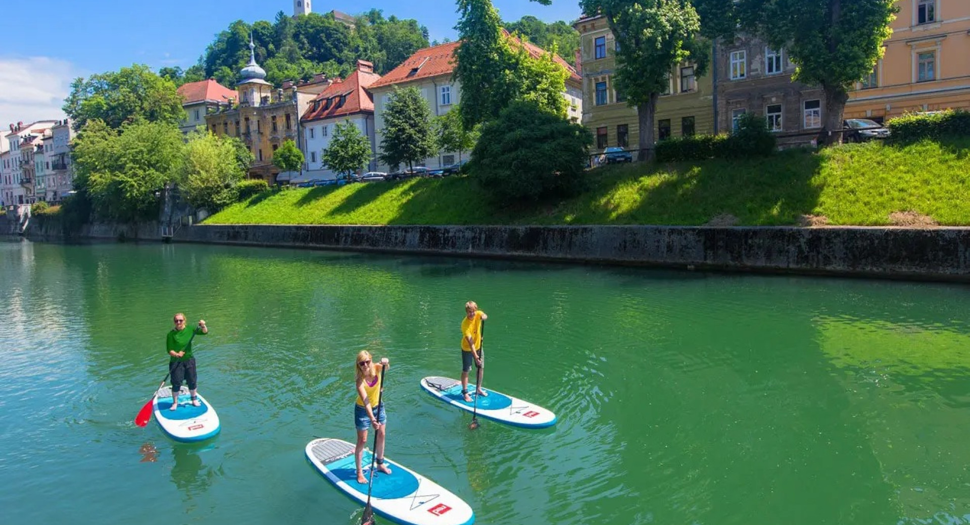 Three people paddling on a SUPs on a river.