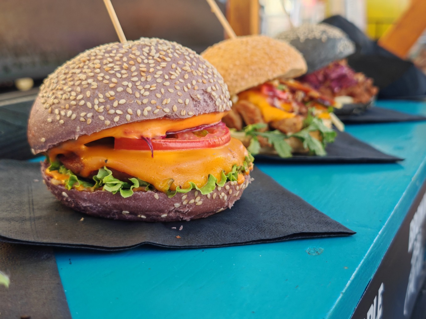 Delicious vegan burgers on a black napkin resting on a blue table.