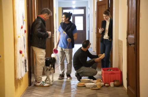 Stirje ljudje in en pes stojijo v hodniku in vsak pocne nekaj drugega.