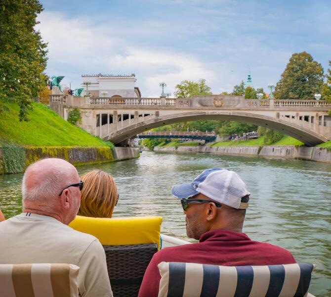 Passengers on board the boat look at the Dragon Bridge from the river level during a cruise on the Ljubljanica.