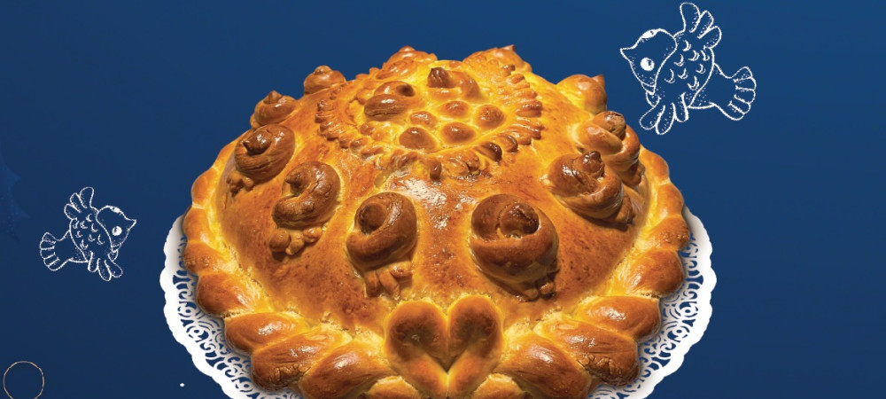 A baked loaf of Christmas bread placed on a table with a dark blue tablecloth.