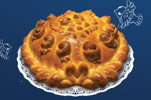 Pecen hlebec bozicnega kruha, postavljen na mizo s temnomodrim prtom.