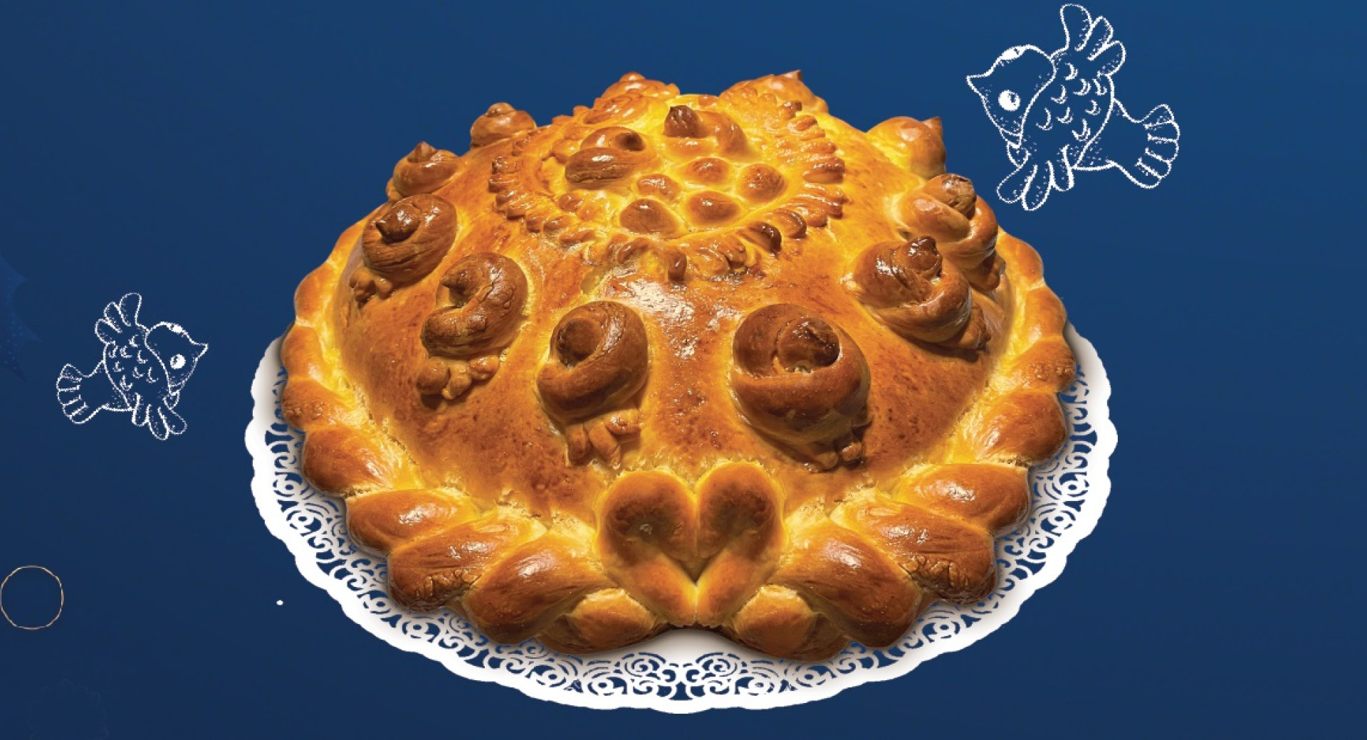 A baked loaf of Christmas bread placed on a table with a dark blue tablecloth.