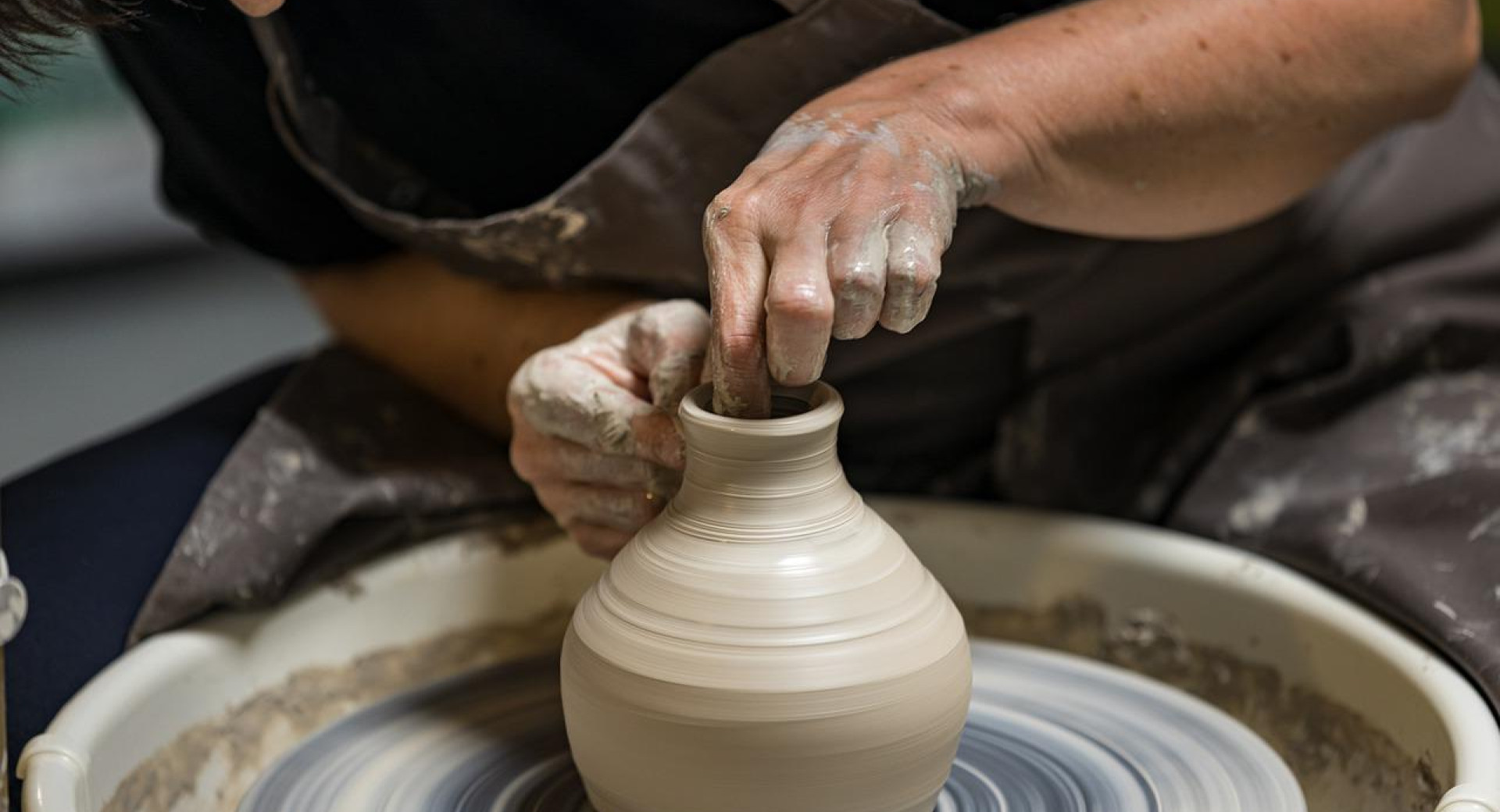 A woman is working on a pottery spindle.