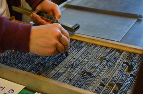 A man arranging letters for print on a printing machine.