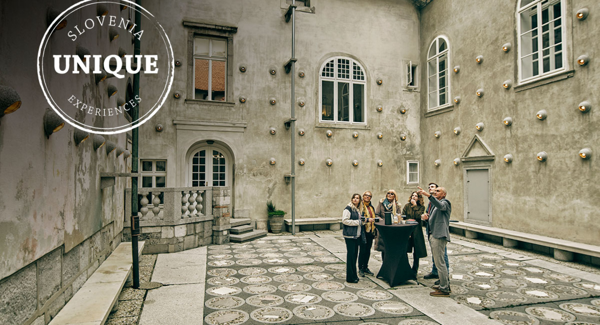 A group of people on the courtyard amidst historical buildings.