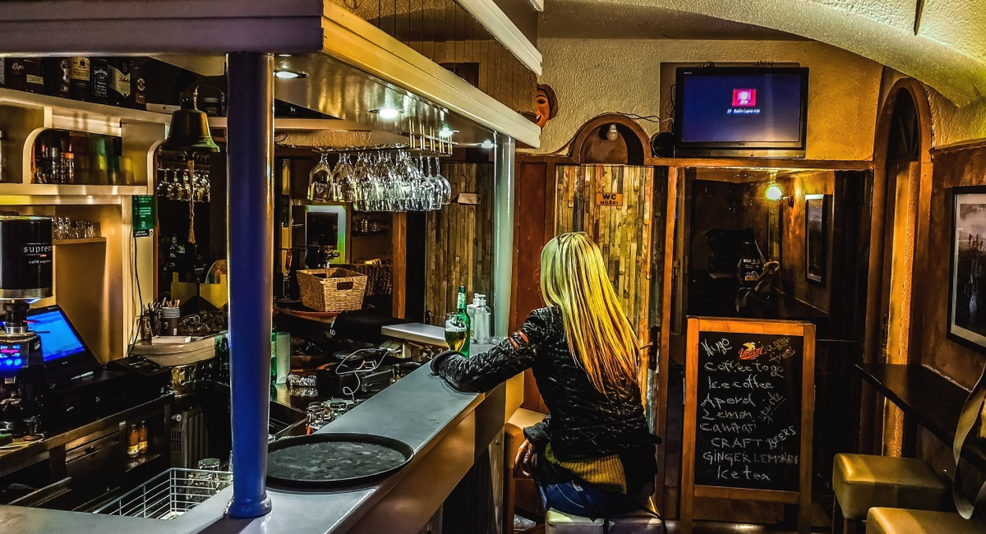 A woman with blond hair sitting behind a bar.