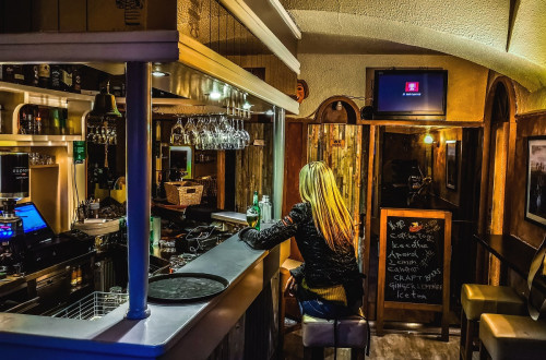 A woman with blond hair sitting behind a bar.