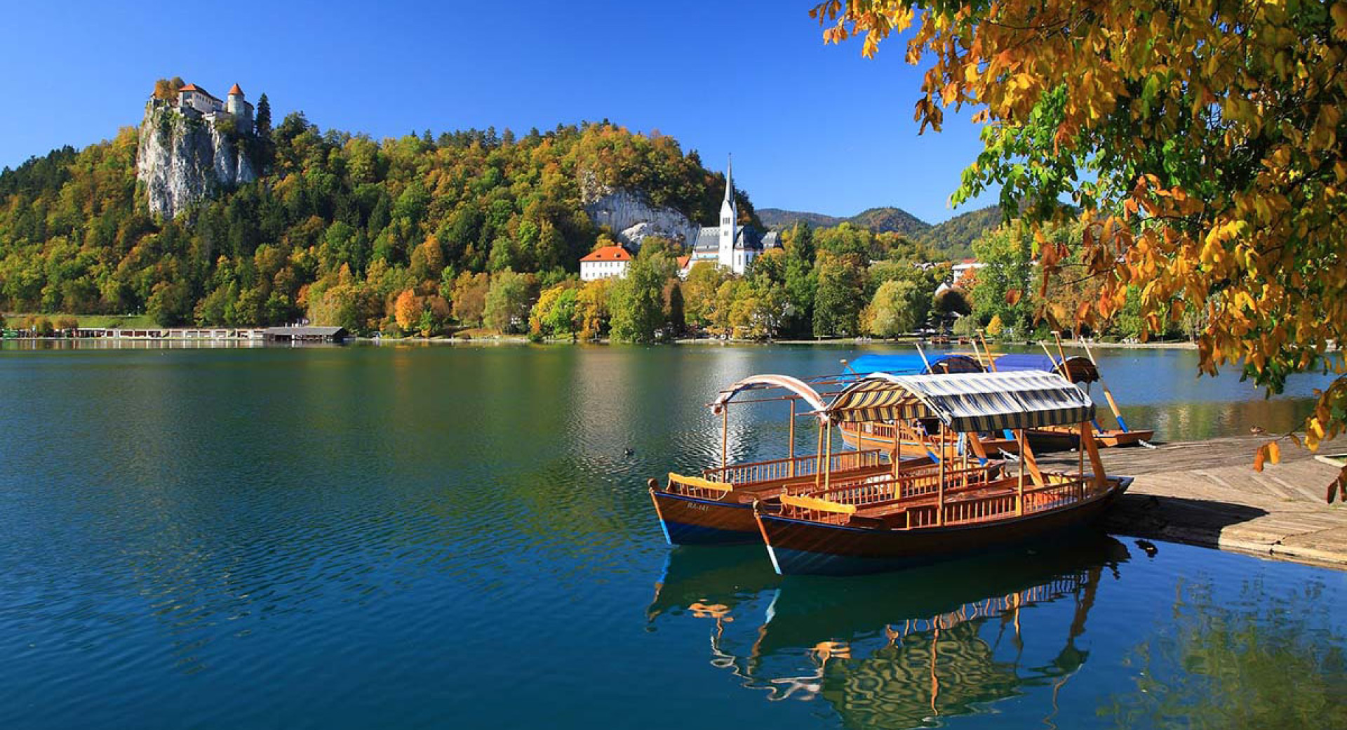 Pletna (barque en bois avec un toit) sur le lac, avec le château de Bled en arrière-plan.