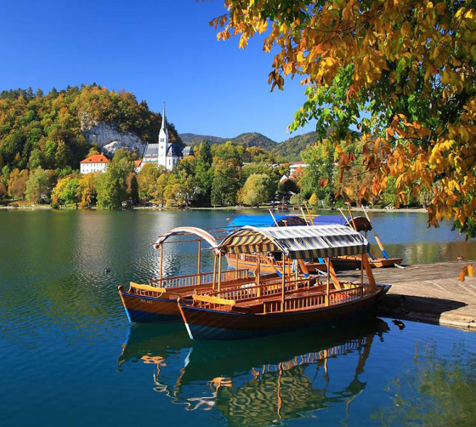 Pletna (wooden boat with a roof) on the lake, with Bled Castle in the background.